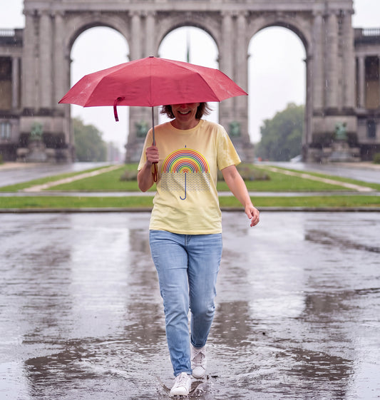 Woman in Lemon Sorbet Surrealism Rain t-shirt with a red umbrella splashing through a puddle at the Cinquantenaire in Brussels in the rain